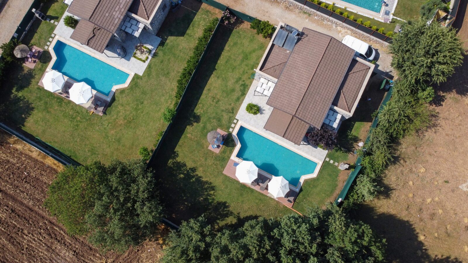 Yan yana iki villa, her biri kendi bahçesi ve havuzuyla