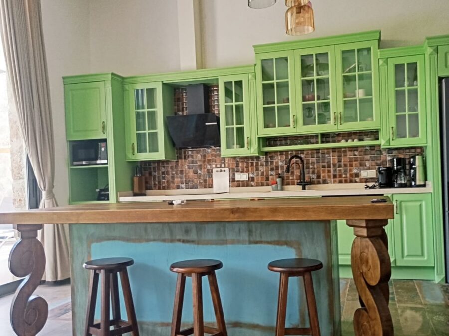 Yeşil ahşap dolaplı mutfak ve bar tezgâhlı ada