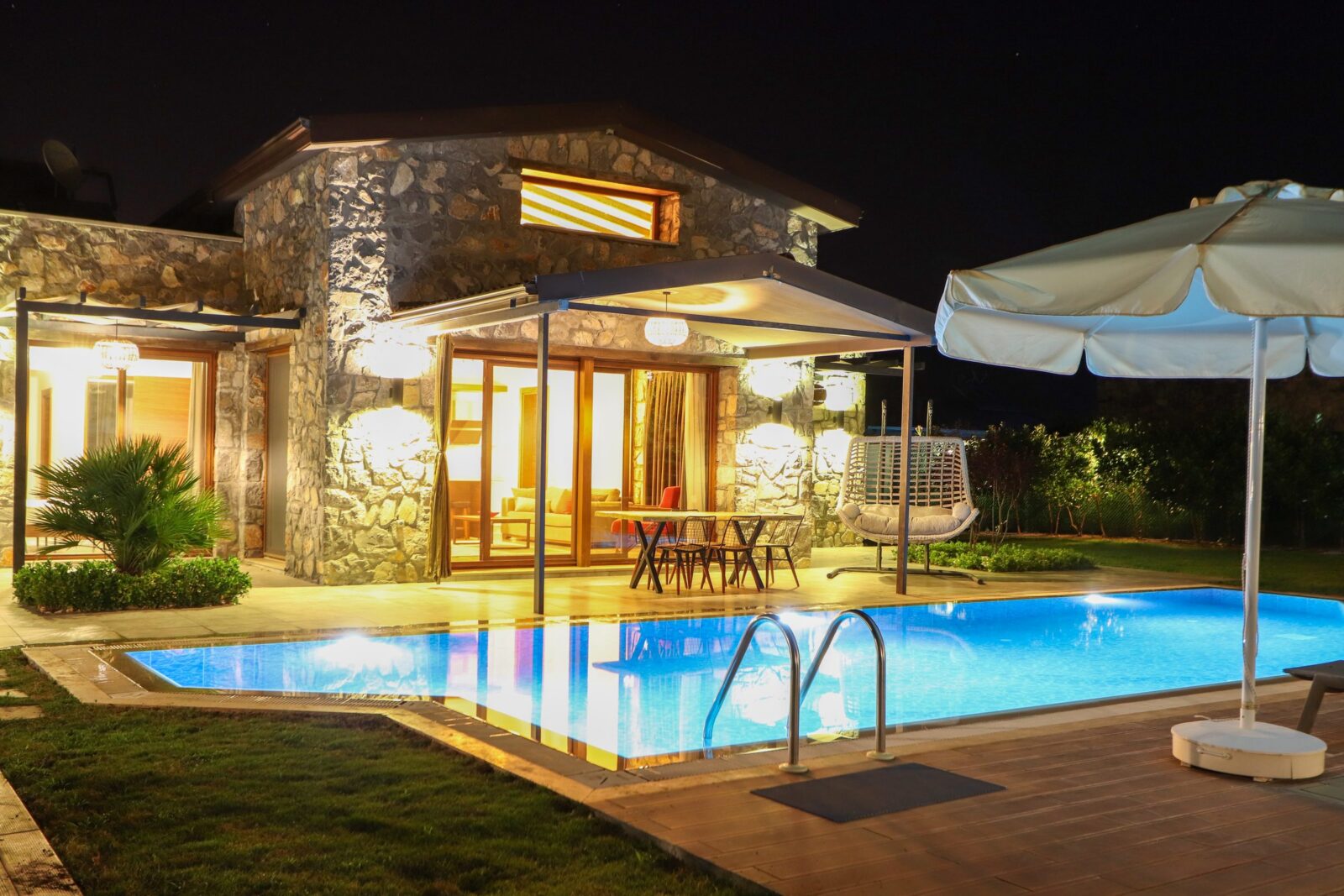 Villa Petunia gece, aydınlatılmış özel havuz ve taş cephe