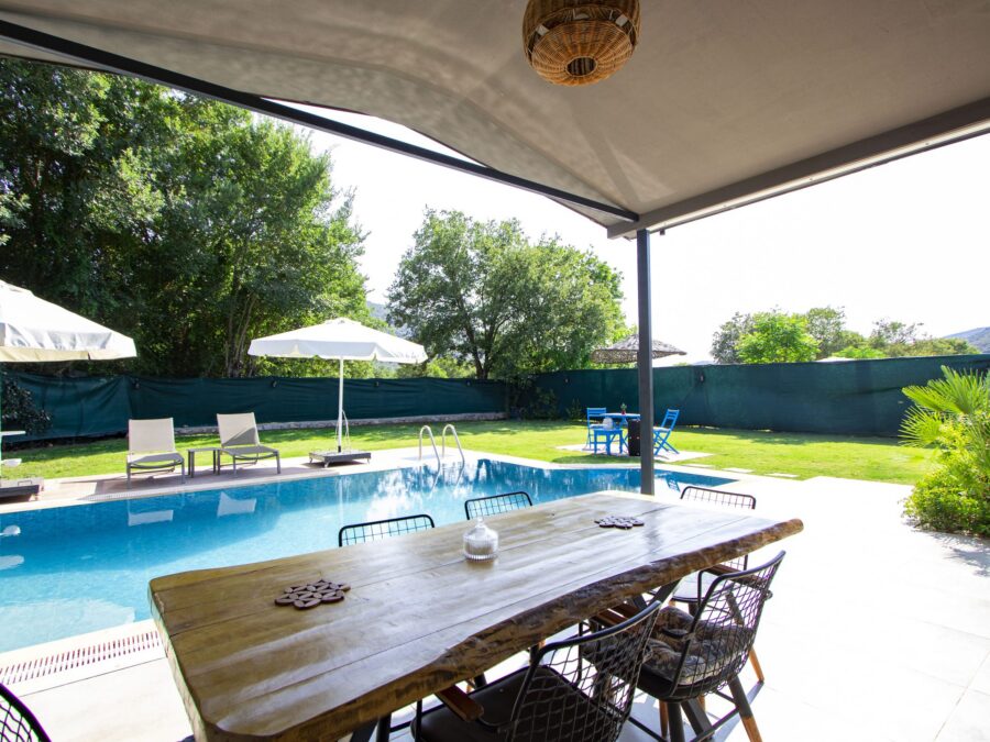 Pergola altında yemek masası, havuz manzarası